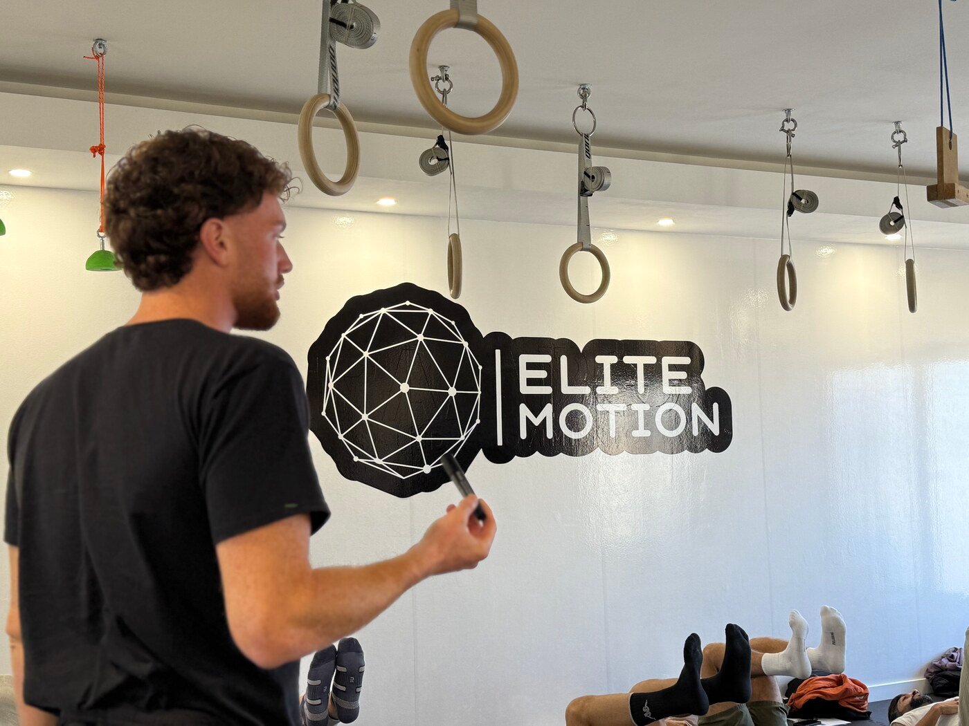 Javier Román señalando el logo de Elite Motion en la pared del centro